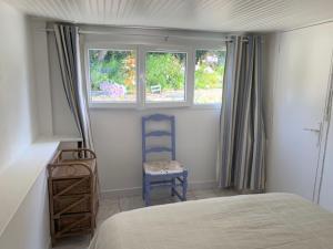 滨海圣洛朗INTERLUDE omaha beach 50 m de la plage的一间卧室配有一张床和一把椅子,还有两个窗户
