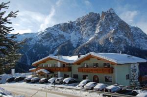 阿尔卑斯休斯山戈斯塔斯旗酒店的山前有车辆停放的建筑物