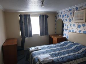 雷丁艾尔姆赫斯特酒店的一间卧室配有一张床、一张书桌和一个窗户。
