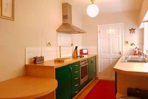 巴克斯顿No 6 The Square Tearooms & Accommodation的厨房配有绿色橱柜和水槽
