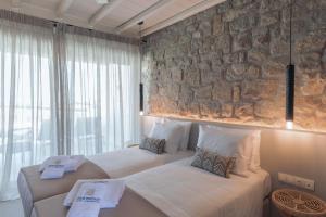 米克诺斯城Aegean Hospitality的石墙客房的两张床