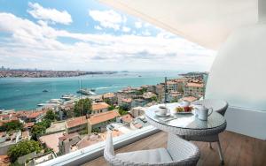伊斯坦布尔博斯普鲁斯歌剧院酒店的阳台配有桌椅,享有海景。