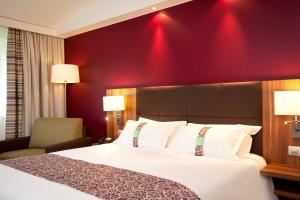 昂格洛里尔西方昂格洛智选假日酒店的酒店客房,设有床铺和红色的墙壁