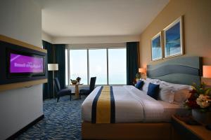 麦纳麦Harbour Suites Hotel的配有一张床和一台平面电视的酒店客房