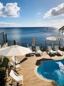 舍尔谢Hotel Pelican的一个带椅子和遮阳伞的游泳池以及大海
