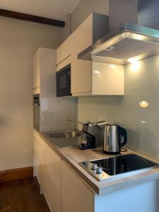 卡迪夫Ty Carreg Fach Staycation Cottage Cardiff的厨房配有白色橱柜和炉灶烤箱。