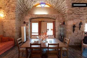 ‘Eilabūn19th Century Magical House in Galilee的一间设有木桌和石墙的用餐室