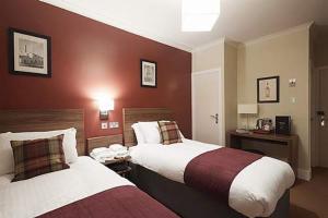 多诺赫鹰酒店的红色墙壁的酒店客房内的两张床