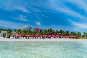 坎昆Grand Oasis Palm - All inclusive的一个带粉红色遮阳伞的海滩和一个度假村