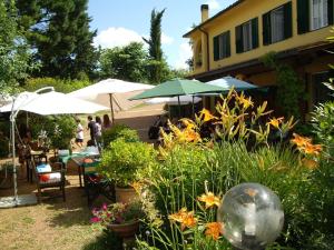 福利亚Tenuta Poggio alla Farnia的花园设有桌椅、遮阳伞和鲜花