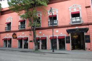 托卢卡Hotel Boutique Margarita Toluca的一条街上有红色遮阳篷的粉红色建筑