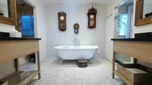 卡梅尔凡噶邦德之家精品酒店的带浴缸的浴室和墙上的时钟