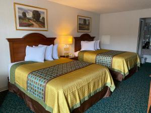HarrisonvilleHarrisonville Inn & Suites的配有黄色床单的酒店客房的两张床