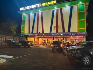 梅劳克Halogen Hotel Merauke的夜间在停车场停车的酒店