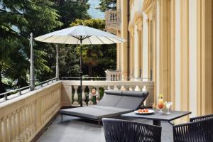 梅纳焦Grand Hotel Victoria concept & spa, by R Collection Hotels的庭院配有遮阳伞和桌椅。
