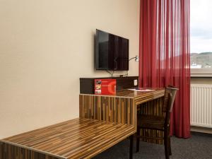 海德堡海德堡酒店的一间设有一张桌子、一台电视和红色窗帘的房间