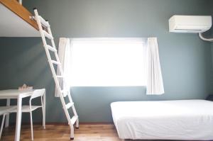 福冈Plusone Nishikoen的一间卧室设有梯子、一张床和一个窗户