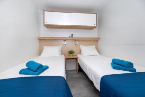 巴什卡沃达Veda Mobile Home的客房内的两张床和蓝色枕头