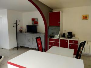 特雷沃 - 特雷吉涅克A 5 mn à pied de la plage的厨房配有红色橱柜和桌椅