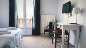 圣雅克·德波尔布吕内酒店的一间卧室配有书桌、一张床和一台电视。