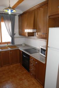 CastellnovoApartamentos Rurales San Juan的厨房配有木制橱柜和白色冰箱。
