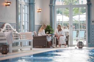 鲁斯特钟岩欧洲主题公园&冒险度假村四星级高级酒店的两个女人坐在游泳池旁的桌子旁