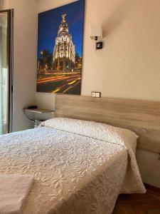 马德里格拉旅馆的一间卧室配有一张床,并拥有一栋建筑的照片