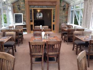 柯库布里Arden House Hotel的餐厅设有木桌、椅子和窗户。