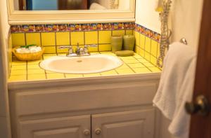 西湾拉斯罗卡斯度假酒店及潜水中心的黄色瓷砖浴室设有水槽和镜子