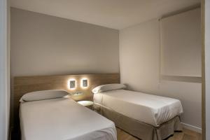 罗萨斯Apartamentos Roses Platja的配有白色墙壁的小客房内的两张床