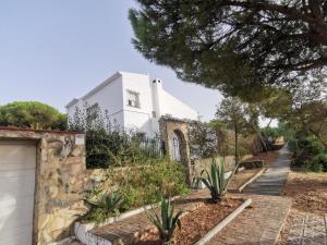 马塔拉斯卡尼亚斯Entre pinos y playa的一座带栅栏和一些植物的白色房子