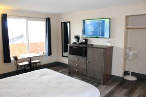 长滩Inn at the Sea的一间酒店客房,配有一张床、一台电视和一张桌子