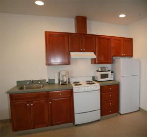 GoldendalePonderosa Motel汽车旅馆的厨房配有木制橱柜、白色炉灶和冰箱。