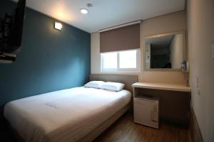 首尔东大门华新旅馆的一间小卧室,配有白色的床和蓝色的墙壁