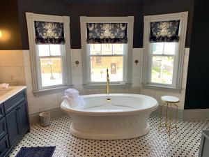 夏洛特顿Slaymaker & Nichols Gastro House & Inn的带浴缸的浴室,设有3个窗户
