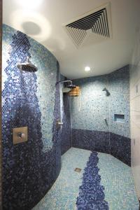 诺因布尔格福尔姆瓦尔德湖滨全景酒店的浴室设有蓝色马赛克瓷砖和淋浴。