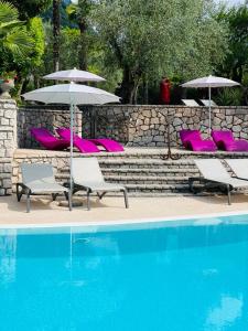 加尔达湖滨Villa Miravalle的一组椅子和遮阳伞,位于游泳池旁