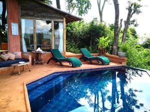 湄斯乐奈富柴塞山度假酒店的一座房子旁的游泳池,配有两把绿色椅子