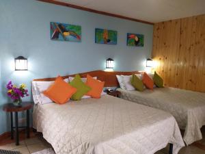 Santa Cruz瓜亚沃酒店的一间卧室配有两张带橙色和绿色枕头的床