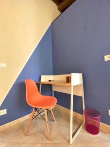 雷焦卡拉布里亚Al Teatro的一张桌子和一张蓝色墙壁旁边的橙色椅子