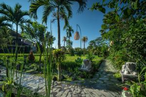 乌布Bliss Ubud Spa Resort的庭院里种有棕榈树和椅子的花园