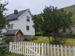SkarsvågNorth Cape family lodge的白色房屋,设有白色的栅栏