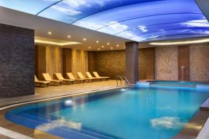 伯萨Ramada By Wyndham Bursa Cekirge Thermal & Spa的酒店大堂的大型游泳池,配有椅子