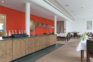 弗赖辛ACHAT Hotel Corbin München Airport的一间拥有红色墙壁的餐厅和一间设有桌子的用餐室