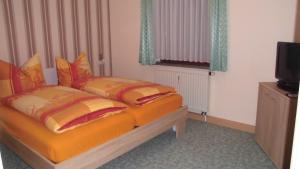 塞芬艾恩科尔弗利恩沃农旅馆的一间卧室配有带橙色床单的床铺和电视。