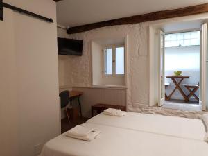 圣地亚哥－德孔波斯特拉迷人的圣马蒂诺旅馆的客房设有两张床和一个带桌子的窗户。