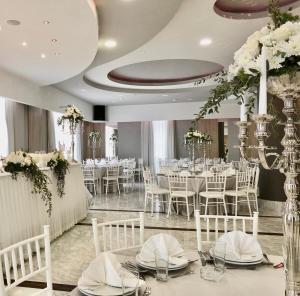 特雷比涅贝尔维尤酒店的宴会厅配有白色的桌子和白色的椅子