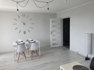 厄尔科Apartament przy promenadzie的白色的房间,墙上有桌子和时钟