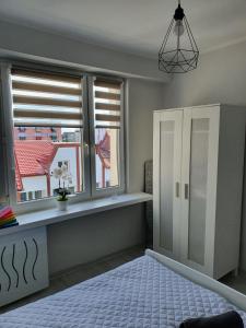 厄尔科Apartament przy promenadzie的一间卧室设有2扇窗户和一张带桌子的床