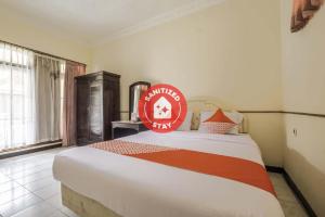 打横Super OYO 2346 Hotel Padjadjaran 1的一间卧室,床上有红色标志